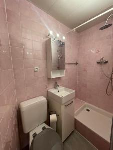 y baño de color rosa con aseo, lavabo y bañera. en Charmant 2 pièces aux portes du Mercantour, en Saint-Martin-Vésubie