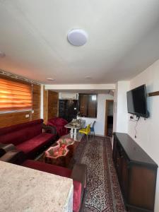a living room with a red couch and a tv at Elegant housing in Jerash