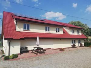 a house with a red roof and a picnic table at Pokoje Gościnne U Kowala in Polańczyk