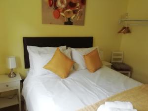 a bed with white sheets and orange pillows at Wilma's Guest House in Dundonnell