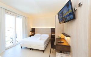 a bedroom with a bed and a television on a wall at Hotel Carducci in Tortoreto Lido