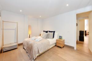 a white bedroom with a bed and a night stand at London Choice Apartments - Covent Garden - Leicester Square in London