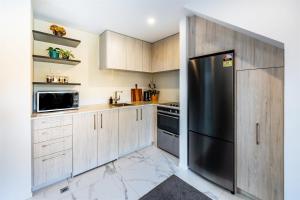 a kitchen with wooden cabinets and a black refrigerator at Stylish home in Christchurch central in Christchurch