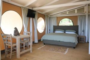 a bedroom with a bed and a table and two windows at Glamping La Ghianda in Elmo