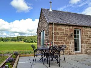 a patio with a table and chairs in front of a building at Kingfisher Cottage in Kirkton of Airlie