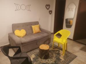 a living room with a couch and a yellow chair at La Lunar un espacio ideal para trabajar y conocer Medellín in Medellín
