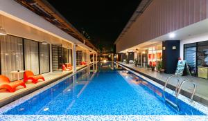 a large swimming pool with orange chairs in a building at The Villa Langkawi in Pantai Cenang