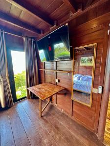GirijatiにあるGlamping Omah Kayu at Watu Paris Jogjaの木製テーブルと窓が備わる木造の客室です。