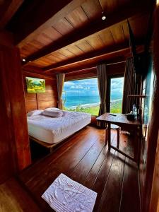 a bedroom with a bed and a view of the ocean at Glamping Omah Kayu at Watu Paris Jogja in Girijati