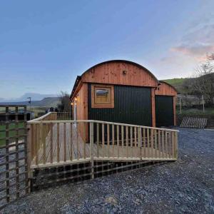 a small wooden cabin with a wooden fence around it at Hafan y Mynydd - Accessible double shepherd hut in Machynlleth