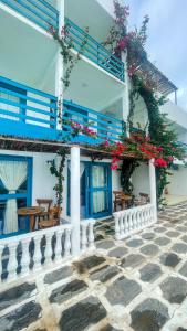 ein weißes Gebäude mit blauen Fenstern und Blumen darauf in der Unterkunft Pousada La Grécia in Camocim