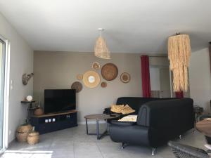 ein Wohnzimmer mit einem Sofa und einem TV in der Unterkunft Coeurs fidèles in Vallon-Pont-dʼArc