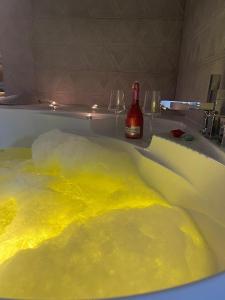 Una bañera llena de limo amarillo y una botella de champán. en Apartman North en Mladenovac
