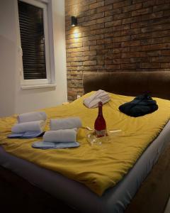 Una cama amarilla con dos almohadas y una botella. en Apartman North, en Mladenovac