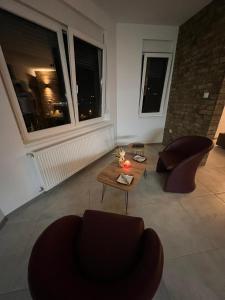 sala de estar con mesa, sillas y ventanas en Apartman North en Mladenovac