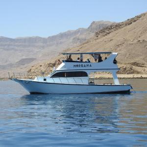 ein weißes Boot im Wasser in der Nähe eines Berges in der Unterkunft Morgana in Ain Suchna