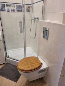 a bathroom with a shower and a toilet with a wooden seat at Kawalerka Gdynia in Gdynia