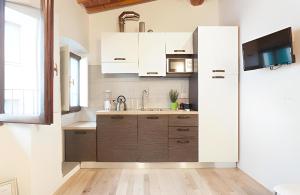La cuisine est équipée de placards blancs, d'un évier et d'un réfrigérateur. dans l'établissement CALIMARA18 25" from Florence AC SmartTV, à Prato