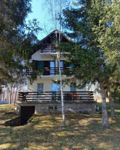 Žune的住宿－Kuća Sarić, Gružansko jezero，一座带门廊和树木的大型白色房屋