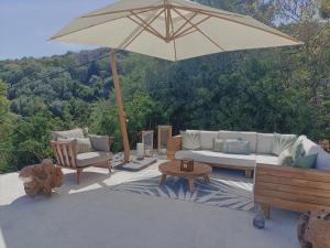 a patio with a couch and an umbrella and chairs at Villa Magnolia in Santa-Maria-di-Lota