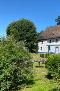 a white house with a tree in the yard at Urlaub in der Natur in Lüdenscheid