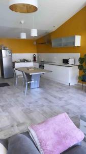 een keuken met een tafel en een keuken met gele muren bij Loft moderne au cœur de l’Auvergne in Thiers