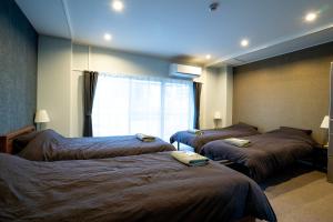 Habitación de hotel con 3 camas y ventana en Usatsuno Osu, en Nagoya