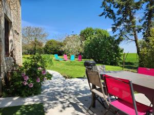 a table with colorful chairs in the grass at Maison chaleureuse et familiale. in Nalliers