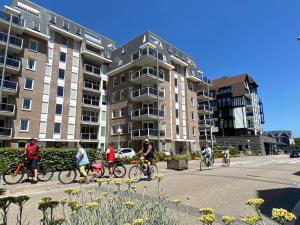 eine Gruppe von Menschen, die mit Gebäuden Fahrrad fahren in der Unterkunft Seaside, Deurloo 53-07 in Cadzand