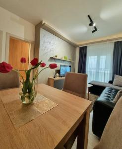 a vase of flowers on a wooden table in a living room at Apartman Rojal Vranje in Vranje