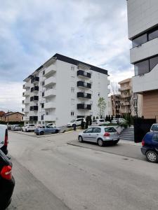 un estacionamiento con autos estacionados frente a un edificio en Apartman Rojal Vranje en Vranje