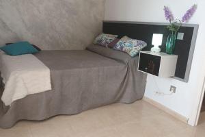 a bed with a gray blanket and a vase on it at ApartPlaya (1ª Línea) in Melilla