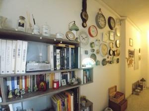 une étagère remplie de livres et d'horloges sur un mur dans l'établissement Miky M House B&B, à Cagliari