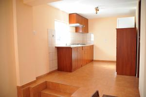 a kitchen with wooden cabinets and a tile floor at Pokoje Gościnne U Kowala in Polańczyk