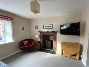 北貝里克的住宿－Charming Cottage in North Berwick with Sea Views，客厅设有壁炉和平面电视。