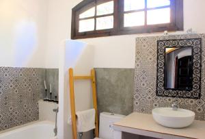 a bathroom with a sink and a tub and a mirror at Dar Maria - Maison d'hôtes in Aouchtame