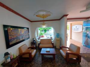 ein Wohnzimmer mit einem Sofa, Stühlen und einem TV in der Unterkunft Hotel San Diego in Yopal