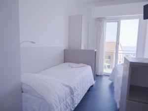 a white bedroom with a bed and a large window at Hotel Liliana in Varigotti