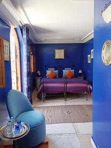 a blue bedroom with a bed and a chair at Dar Taliwint in Marrakesh