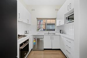 una cucina bianca con lavandino e lavastoviglie di Burwood City Newly renovated 2 Bed 2 Bath Free Private Parking Big Apt a Sydney