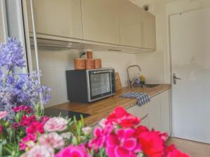 eine Küche mit einer Mikrowelle und Blumen auf der Theke in der Unterkunft La Voulzie Appartement - Proche centre avec parking privé in Provins