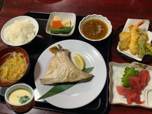 un plateau de nourriture avec une plaque de poisson et d'autres aliments dans l'établissement 民宿ニュー万福茶屋, à Taketa
