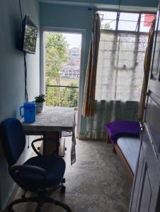 Zimmer mit einem Tisch, einem Bett und einem Fenster in der Unterkunft Winnie's Lodge in Shillong