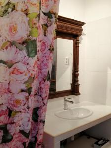 a bathroom with a sink and a shower curtain with pink roses at La Campagne en Ville in Laragne