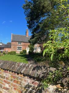 una casa con una pared de ladrillo y un árbol en Boothorpe Farmhouse en Blackfordby