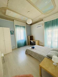 a bedroom with a bed and a table and two windows at Deodato Guest House in Catania