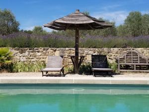 2 sillas y sombrilla junto a la piscina en Domaine du Coffre en Pertuis