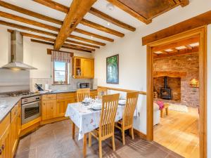 una cocina con armarios de madera y una mesa con sillas. en The Lodge, en Lydney