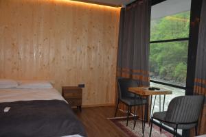 a bedroom with a bed and a desk and a window at DOĞAL SUİT BUNGALOV in Ardeşen
