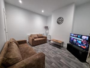 een woonkamer met een bank en een flatscreen-tv bij Manchester St by Prestige Properties SA in Barrow in Furness
